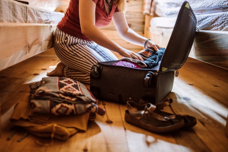 Woman packing suitcase in log cabin by Rose Pest Solutions