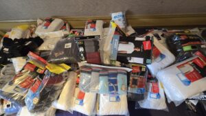 Several packages of men's underwear, socks, and t-shirts from various brands, including Hanes and Gildan, are spread out on the floor.