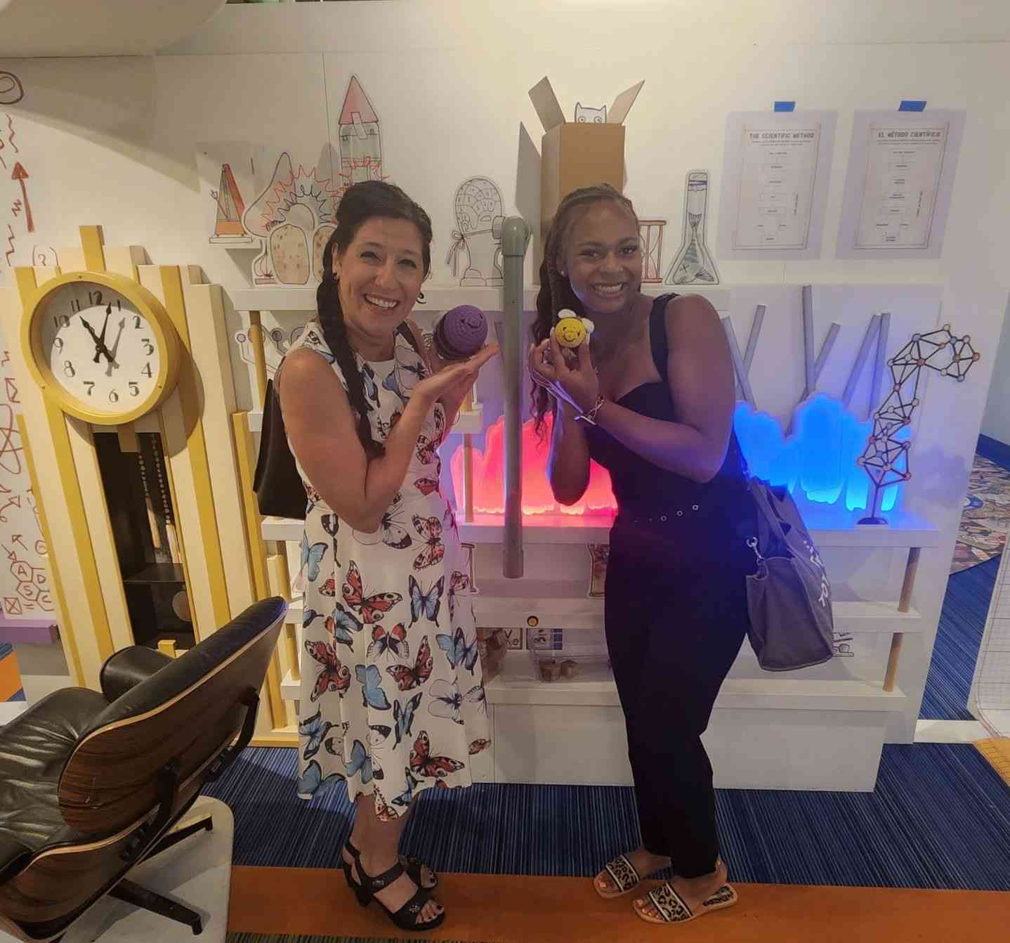 Holding Small Objects Two people holding small objects at a science exhibit with a colorful display background