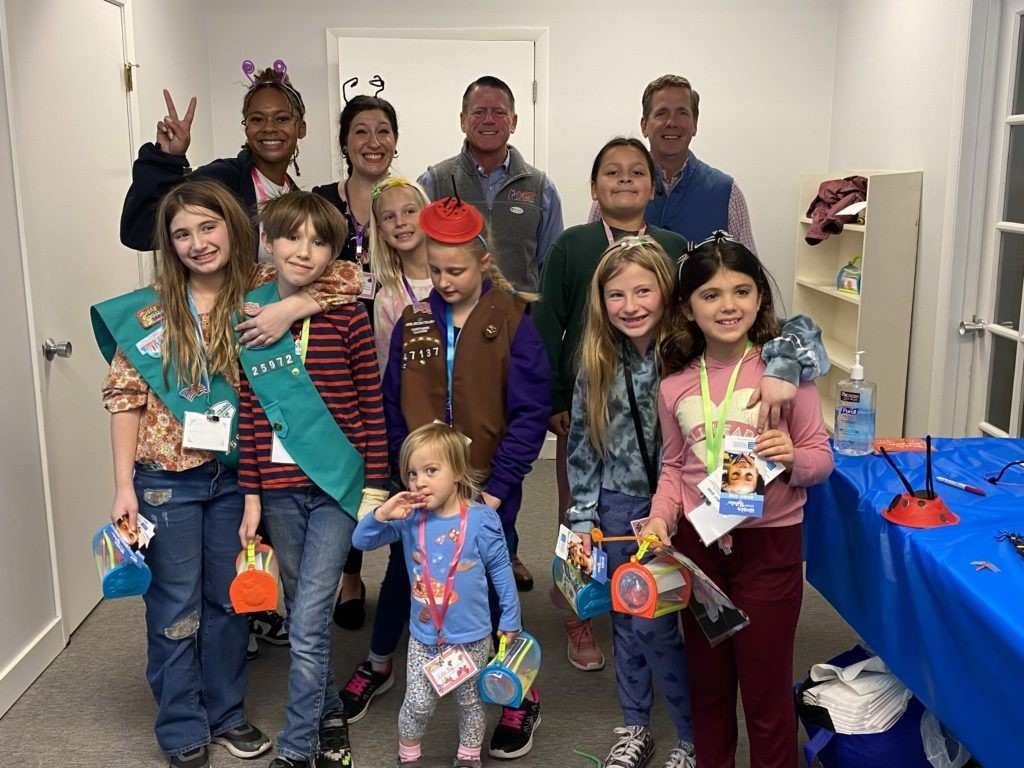Group of children and adults posing indoors with badges, medals, and event giveaways